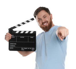 Making movie. Smiling man with clapperboard pointing at camera on white background