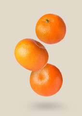 Fresh ripe tangerines in air on beige background
