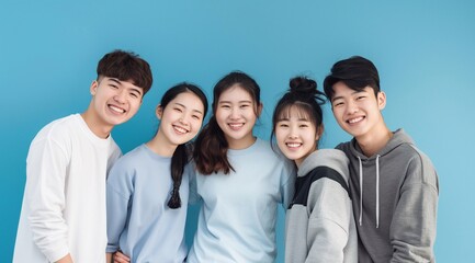 Obraz premium A portrait of korean young people early twenties. standing close together against an isolated blue background. They wear casual t-shirts or hoodies, exuding youthful happy energy. generative AI