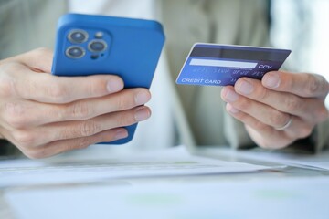Asian Man paying with credit card on smart phone at office. Male Using Smartphone for Shopping electronic wallet Online