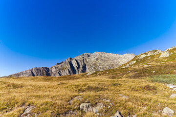 Alpine landscape with rocks and grass at Swiss mountain pass St. Gotthard on a sunny late summer day. Photo taken September 10th, 2023, Gotthard, Switzerland.