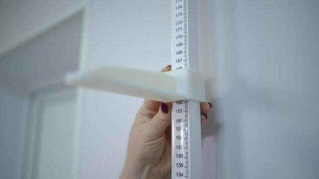 Slow motion. Close-up. A woman's hand moves down the bar of a stadiometer in a doctor's office during a medical examination in a clinic