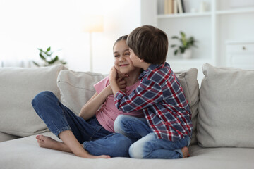 Obraz premium Happy brother and sister spending time together on sofa at home