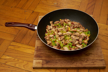Chinese fried chicken with vegetables in wok frying pan