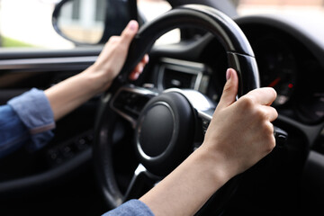 Woman holding steering wheel while driving her car, closeup