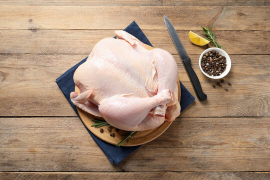 Fresh raw chicken with spices and knife on wooden table, flat lay