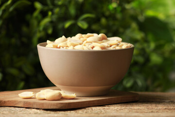 Fresh peanuts in bowl on wooden table against blurred background