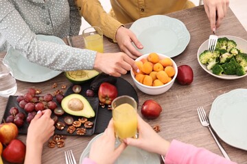 Friends eating vegetarian food at wooden table indoors, closeup