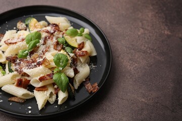 Tasty pasta with bacon and basil on brown table, space for text