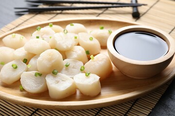 Raw scallops with green onion and soy sauce on dark table, closeup