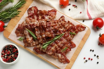 Slices of tasty fried bacon with different spices and tomatoes on light table, flat lay