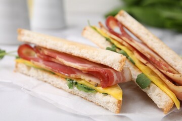 Delicious sandwiches with bacon on white table, closeup