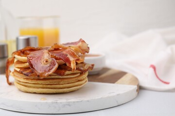 Delicious pancakes with bacon and honey on white table, closeup. Space for text