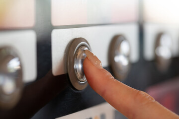 自動販売機のボタンを押す女性の手