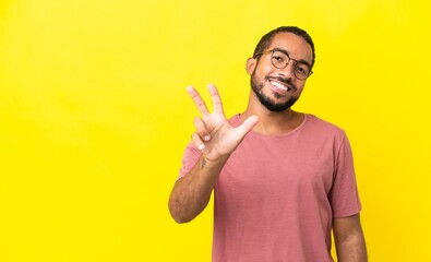 Fototapeta premium Young latin man isolated on yellow background happy and counting three with fingers