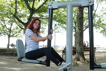 young woman on training apparatus in the park