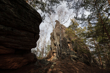 High rocks among trees in the mountains. Traveling and hiking in mountainous areas. Nature of Siberia. Krasnoyarsk Pillars, Krasnoyarsk region, Russia.
