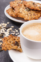 Cup of coffee with milk and homemade oatmeal cookies on white plate. Delicious crunchy dessert