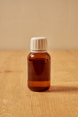 Red, empty glass medicine bottle on a wooden table.