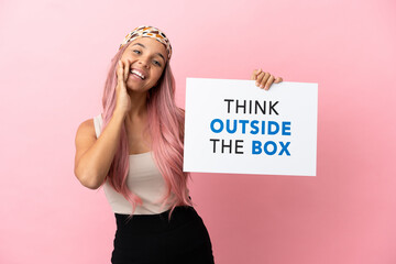 Young mixed race woman with pink hair isolated on pink background holding a placard with text Think...