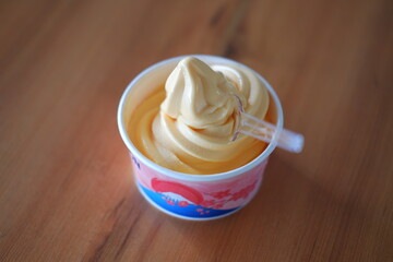 ice cream in paper cup on wood table background. soft focus.