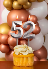 Cupcake with birthday candle on balloons background - Number 52