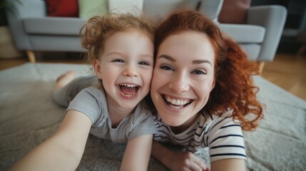 A mother with red curly hair and her smiling toddler enjoy a playful moment on the floor, their faces glowing with joy and laughter