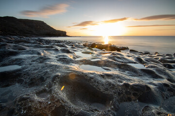 View of the sunrise over the Atlantic Ocean. View over a stone beach of a volcanic island. Cold...