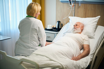 Obraz premium Nurse sitting on a bed near an old man
