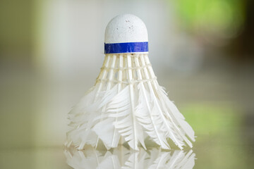 A close up photo of a used shuttlecock which has been used repeatedly with its feathers starting to...
