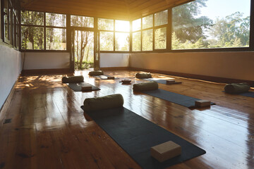 Empty clean gym wellness center interior with big windows for group retreats sessions in natural forest garden area. Modern studio for yoga meditation practices background with mats on wooden floor.