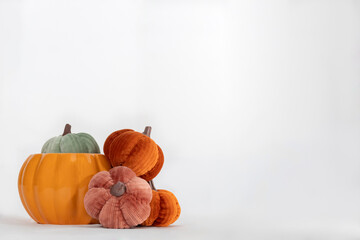 One Ceramic Pumpkin Plus Four Fabric Pumpkins in Various Colors on Left Side of White Background, no people, horizontal