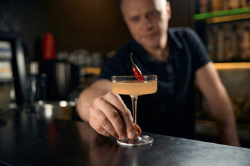 Professional man bartender serving signature vanilla-white cocktail