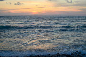 Warm waves of the Mediterranean sea and a sandy beach at sunrise