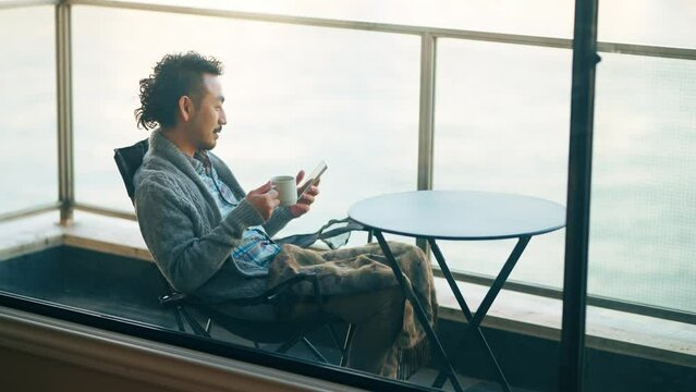 ベランダでリモートワークする髭の男性
