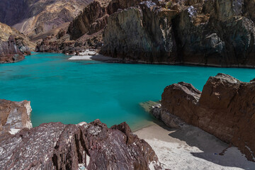 Naklejka premium Landscape of sandy beaches amidst Jagged Mountain rocks and clear green water In Ladakh.
