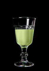 Glass of absinthe on black background