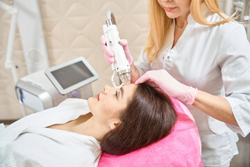 Client undergoing radio frequency microneedling treatment by cosmetologist