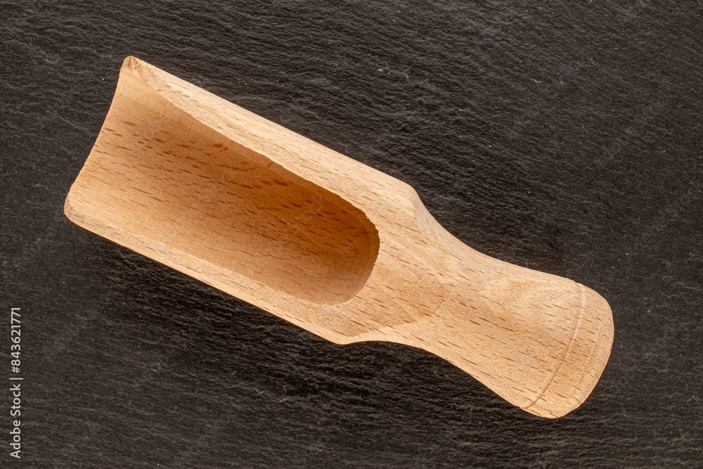 Poster One wooden kitchen spatula on slate stone, macro, top view.