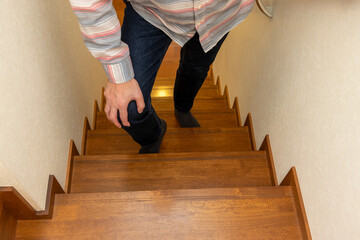 膝を押さえながら階段を上る