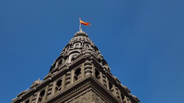 Saffron color flag symbol of hindu culture waving on top of temple of lord Shri Rama, Sajjangad, Satara India.