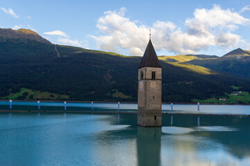 Lake Reschensee and mountain alps panorama with steeple (bell tower) of submerged church in South Tyrol, Italy