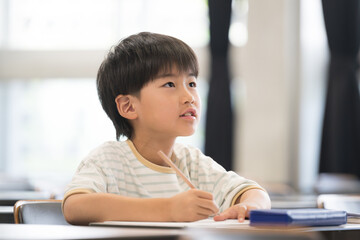 教室で授業中に勉強をし鉛筆を持つ小学生の男の子　見上げて黒板を写す