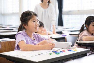 教室で授業中に勉強をし鉛筆を持つ小学生の女の子見上げて黒板を写す　複数