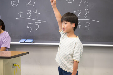 Elementary school boy studying math on the blackboard Hi! I did it!