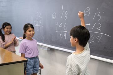 黒板で算数を勉強する小学生複数　よくできましたと拍手