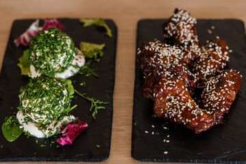 Baked chicken wings in soy honey sauce with sesame seeds on a black board