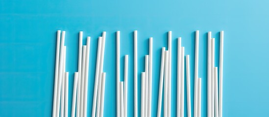 Obraz premium Stainless steel straws lay over white plastic straws on blue background flat lay top view zero waste concept. copy space available