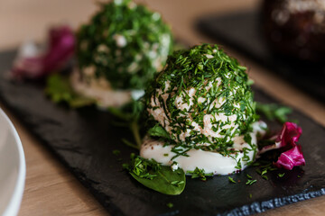 Cheese balls with herbs on a black board on a white background