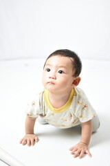 Fototapeta premium A curious baby with bright, wide eyes and a gentle expression, crawling on the floor. Dressed in a cute, animal-themed outfit, the baby looks upwards, capturing a moment of innocent wonder.